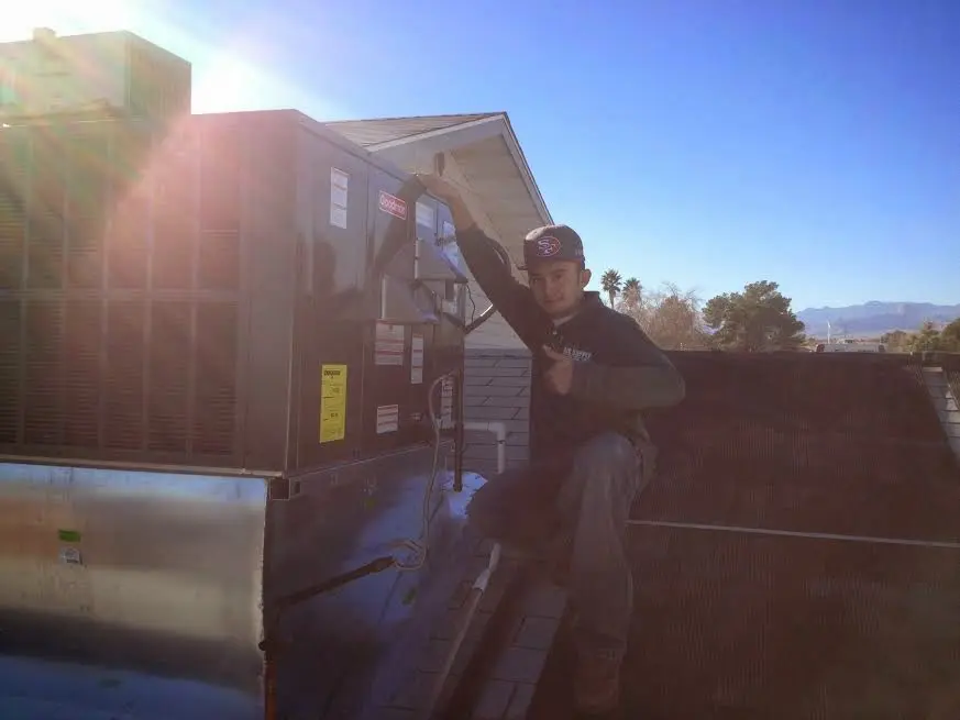 HVAC technician performing AC Tune-Up on a rooftop unit in Natchez