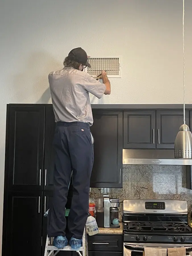 Technician inspecting an air vent during HVAC service in Natchez